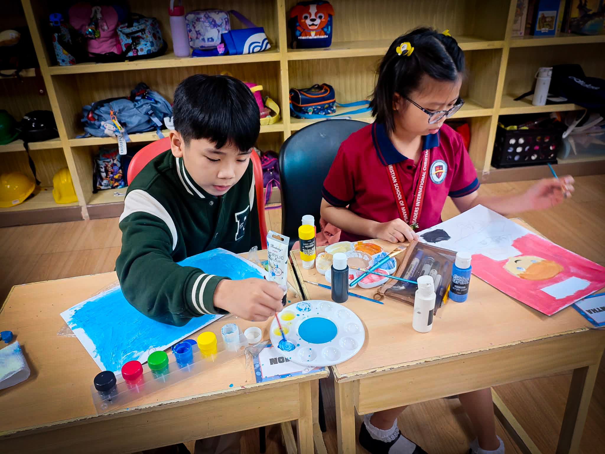 Elementary students painting together during an art class at Leaders.