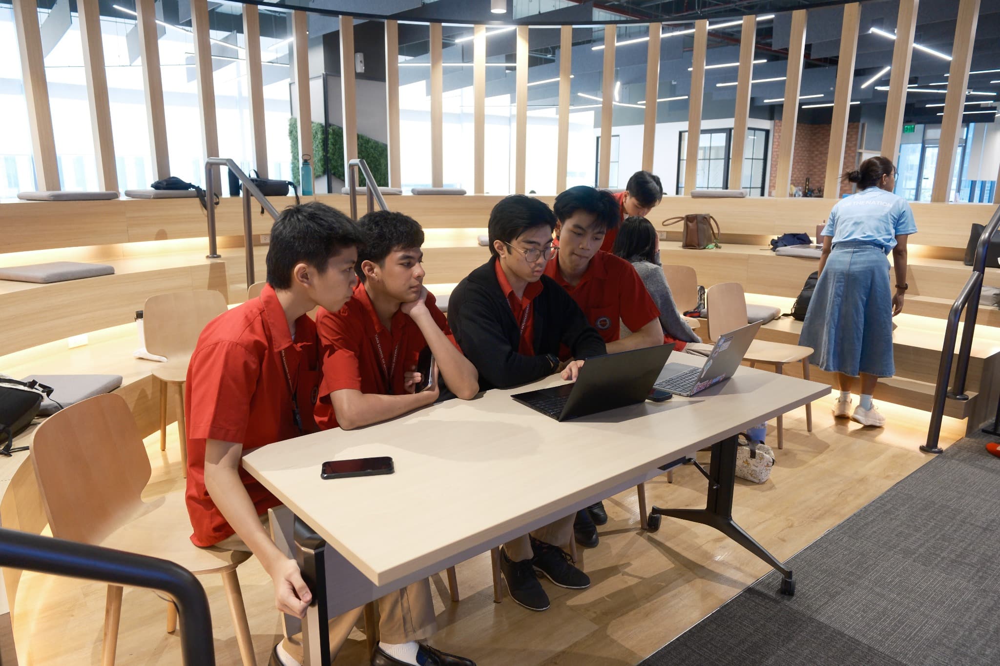 Junior high students working together around a laptop.