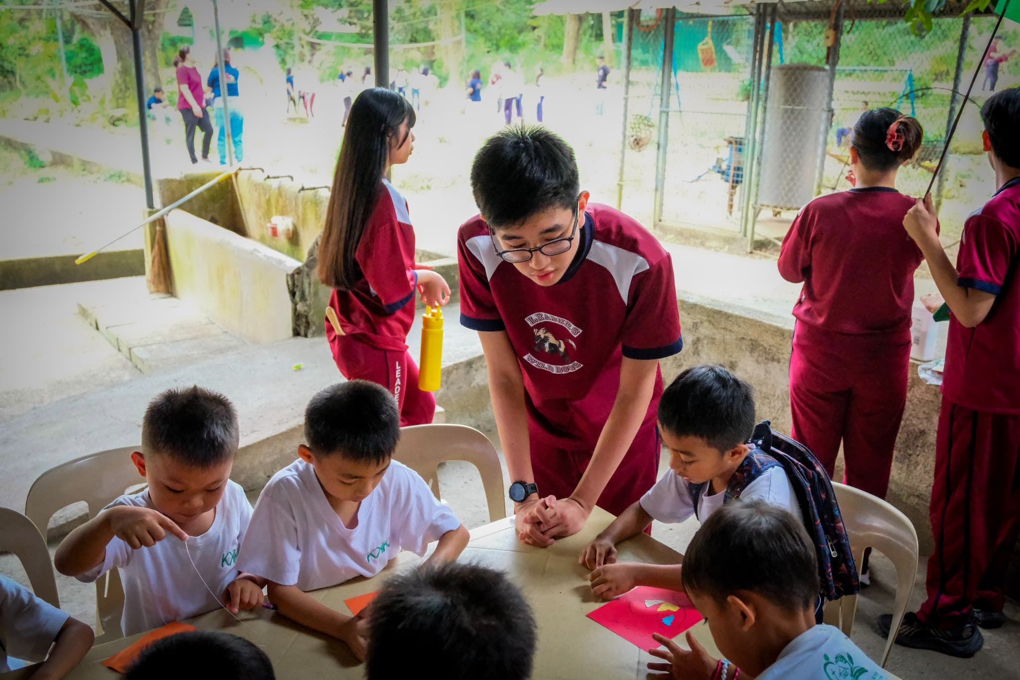 An older student at Leaders guiding younger students during a group activity.