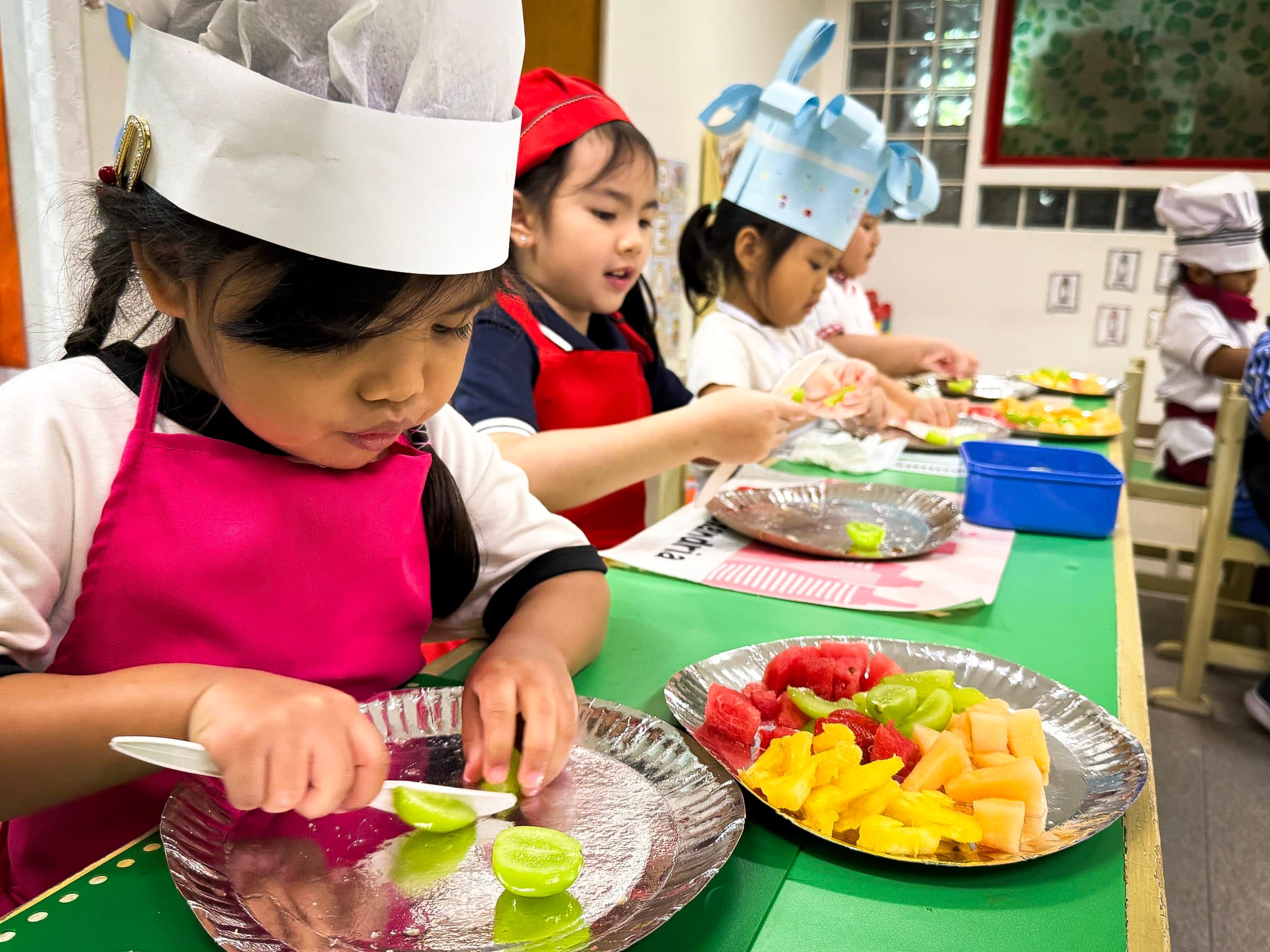 Preschool students preparing fruit during a hands-on classroom activity.